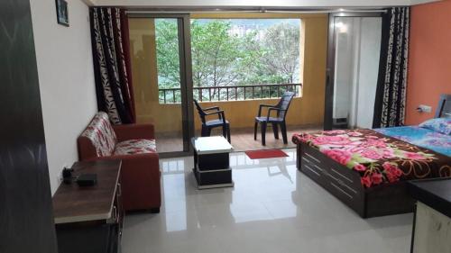 a living room with a bed and a balcony at Studio Apartment On The Lake in Lavasa