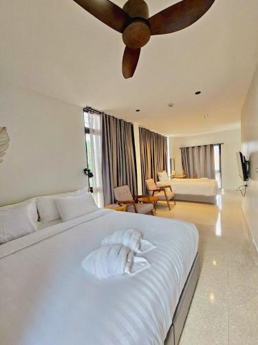a bedroom with a large white bed with a ceiling fan at Calamint Residence Hotel ( คาลามิ้นท์) in Chumphon