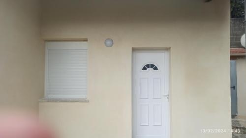 une porte blanche dans un mur blanc avec une fenêtre dans l'établissement maison neuve - le laos -, à Les Ageux