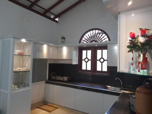 cocina con armarios blancos, ventana y fregadero en JANA HOUSE en Galle