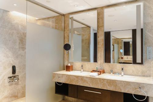 a bathroom with two sinks and a large mirror at Four Points by Sheraton Qingdao, West Coast in Huangdao