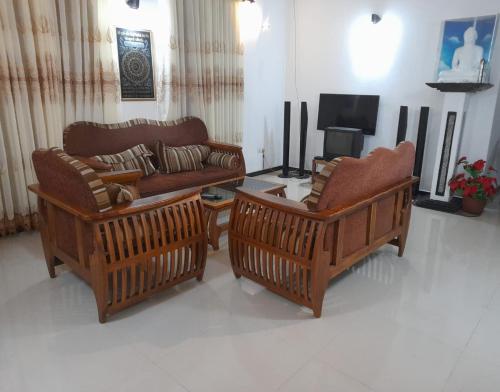 a living room with two couches and a tv at JANA HOUSE in Galle