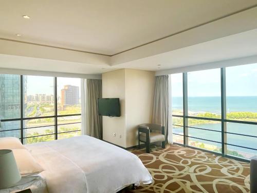 a hotel room with a bed and a view of the ocean at Four Points by Sheraton Qingdao, West Coast in Huangdao