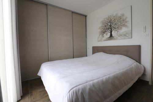 um quarto com uma cama branca e portas de vidro deslizantes em MAISON à AJACCIO tout CONFORT 4-5pers em Ajaccio