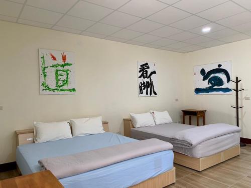 twee bedden in een kamer met bij People Hostel Taiwan Image Calligraphy Museum in Baihe