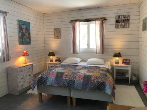Villa Stuga في Hammarstrand: غرفة نوم بسرير وطاولتين ونافذة