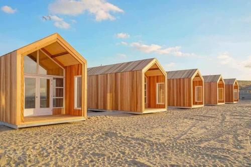 a row of wooden houses sitting in a field at Sisters Beachbungalows in Katwijk aan Zee