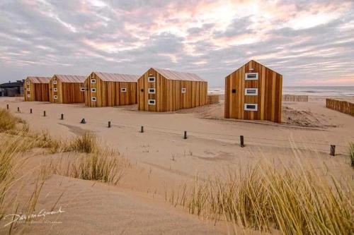 una fila de casas de madera en la playa en Sisters Beachbungalows, en Katwijk aan Zee