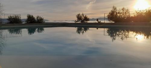 a pool of water with the sun setting in the background at Quinta Alto da Fraga in Vila Nova de Foz Coa