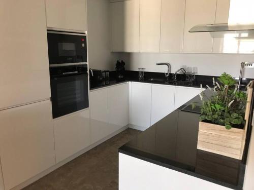 a kitchen with white cabinets and a black appliance at Spectacular sea views apartment in Gibraltar