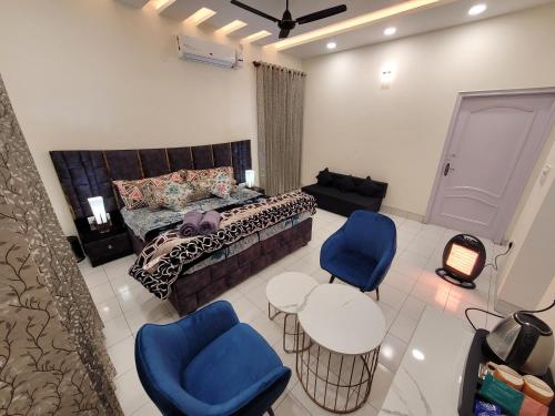 a bedroom with a bed and two blue chairs at Regalia Home Sapphire Stay in Jammu