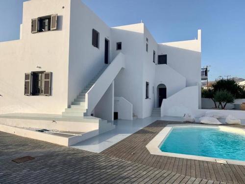 a white house with a swimming pool in front of it at The Blue Lagoon Apartment in Aliki