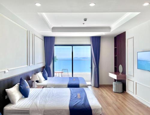two beds in a hotel room with a view of the ocean at TMS Quy Nhơn View Biển in Quy Nhon
