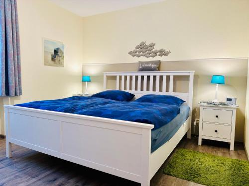 - une chambre dotée d'un lit blanc avec des draps bleus et des oreillers bleus dans l'établissement Schloss am Meer Whg 10, à Büsum