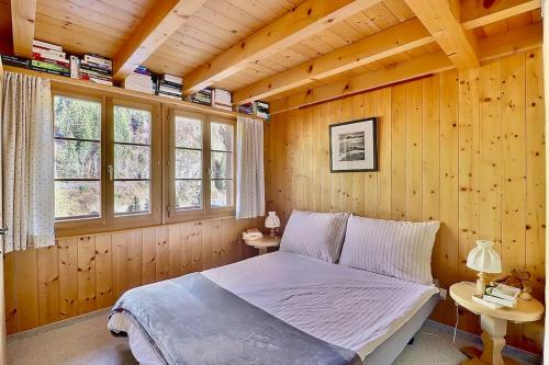 - une chambre avec un lit dans un mur en bois dans l'établissement Duplex des Préalpes fribourgeoises, à Jaun