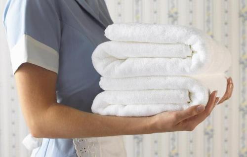 a woman holding a stack of white towels at bHOTEL Yutori - 1BR Apartment in Onomichi for 3 Ppl in Onomichi