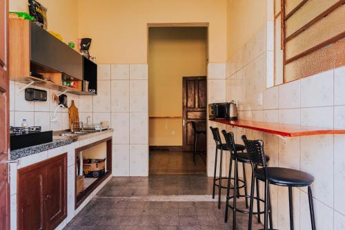 a kitchen with a bar with stools in it at Hostel Casarão Fronteira in Santana do Livramento