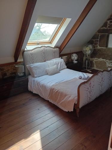 ein Schlafzimmer mit einem Bett und einem Fenster im Dachgeschoss in der Unterkunft L'Annexe in Maël-Pestivien