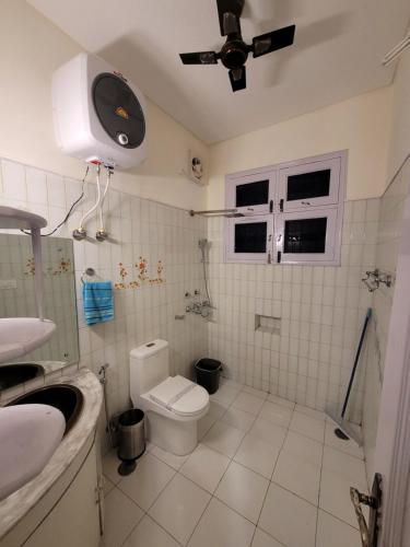 a bathroom with a toilet and a ceiling fan at Regalia Home Sapphire Stay in Jammu