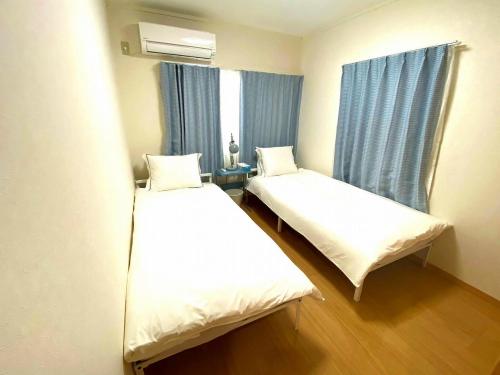 2 łóżka w małym pokoju z oknem w obiekcie 麗base野芥 w mieście Fukuoka
