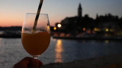 una persona che tiene in mano un bicchiere di birra con una cannuccia di Hotel Glavovic a Lopud