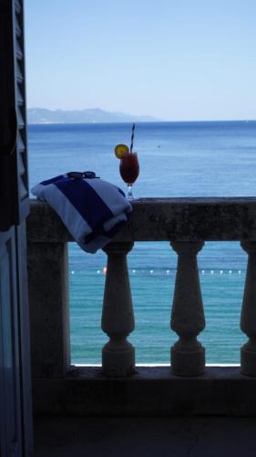 an apple and an umbrella on a balcony with the ocean at Hotel Glavovic in Lopud Island