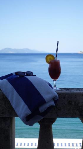 a drink sitting on a railing with a view of the ocean at Hotel Glavovic in Lopud Island