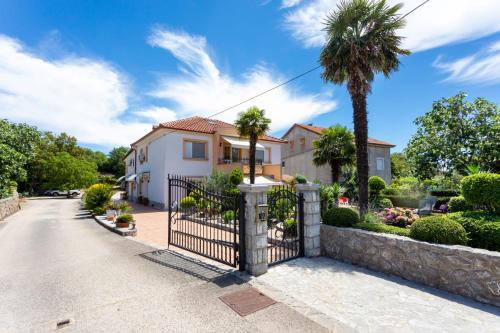 a house with a fence and palm trees at Apartment Marangunija in Malinska