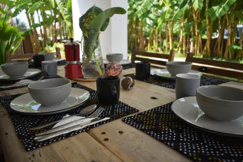einen Holztisch mit Tellern, Tassen und Küchenutensilien in der Unterkunft Villa Julito, Kiwengwa in Kiwengwa