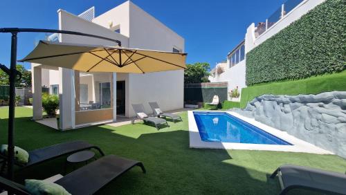 a backyard with a swimming pool and an umbrella at Villa Paraiso-Luxury Villa with Heated Pool in Adeje