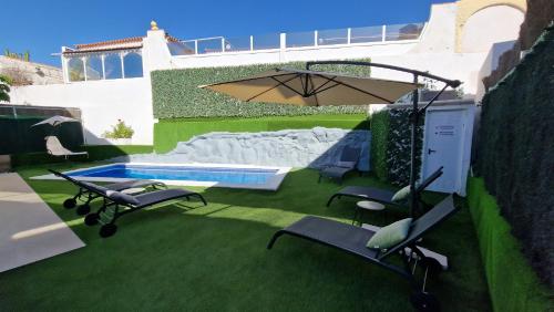 a patio with chairs and an umbrella and a pool at Villa Paraiso-Luxury Villa with Heated Pool in Adeje