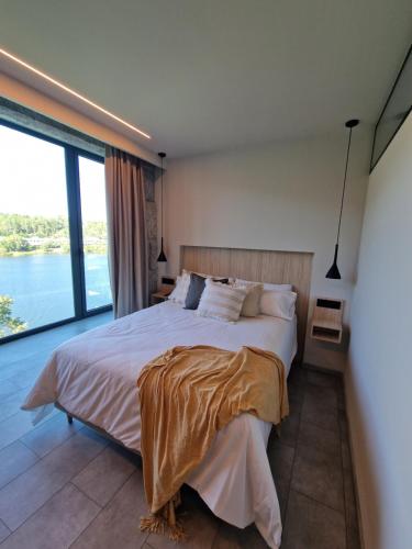 a bedroom with a large bed and a large window at Casa do Barqueiro LOUREIRA in Castrelo de Miño