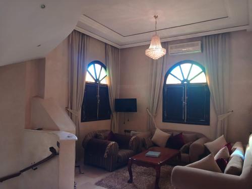 uma sala de estar com um sofá e duas janelas em Villa Mima em Marrakech