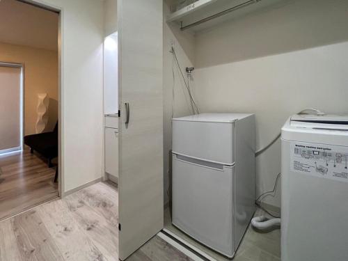 a small kitchen with a white refrigerator in a room at Yutori by b hotel - Cozy 1Br Apartment for 3Ppl in Onomichi City in Onomichi