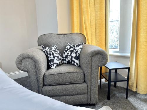a chair with two pillows on it next to a window at Contractor HQ Spacious & Central 4 Bed Home in Newcastle upon Tyne
