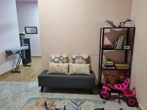 a living room with a couch and a shelf with books at Umar's Tiny House in Kampong Kemaman