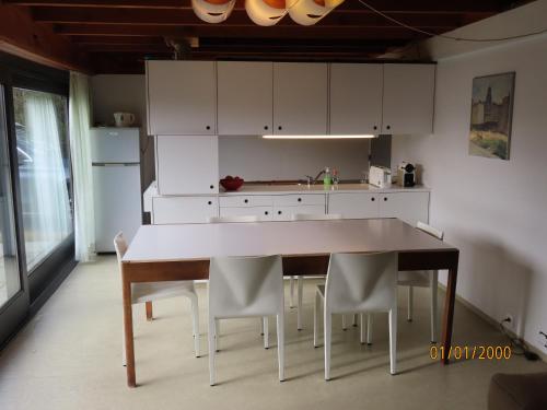 eine Küche mit weißen Schränken sowie einem Tisch und Stühlen in der Unterkunft vakantiehuis Veerse Meer met grote privétuin in Kamperland