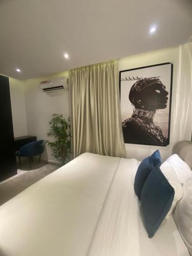 ein Schlafzimmer mit einem weißen Bett mit einem Bild an der Wand in der Unterkunft affordable Apartment in Lagos