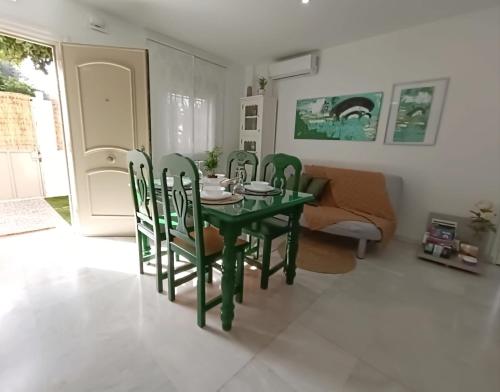 a dining room with a green table and chairs at Nao Victoria in Gelves