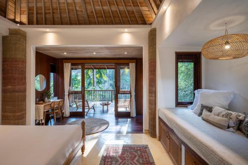 een woonkamer met een bed en een balkon bij The Kayuan Lumbur Resort Ubud in Ubud