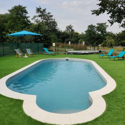 a swimming pool in a yard with chairs and an umbrella at Tipi Apache des monteaux in Vivy