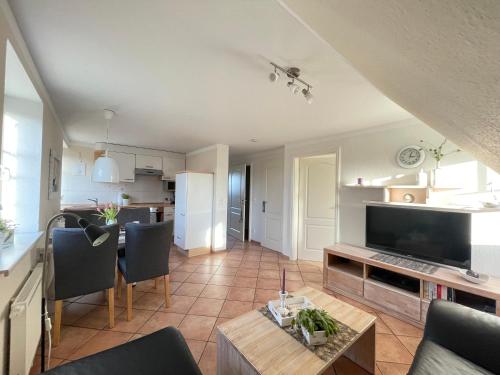 a kitchen and a living room with a television and a table at Haus Wyden in Utersum