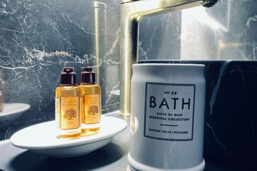 two bottles of bath oils sitting next to a sink at Love Room Le Baroque / Jacuzzi / Sauna in Château-Landon