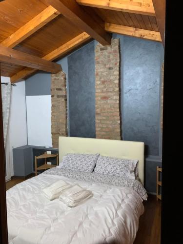 Schlafzimmer mit einem großen weißen Bett und Holzdecken in der Unterkunft Casetta fra ely in Meda