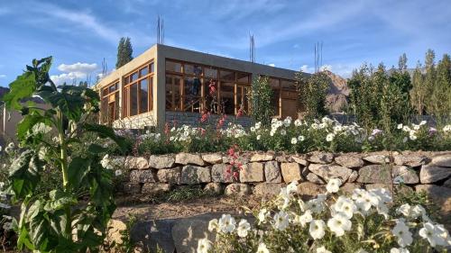 una casa con una pared de piedra y flores en Nordica Resorts Ladakh, en Leh