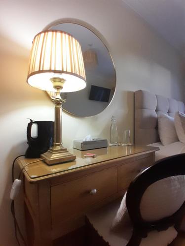 a lamp on a table with a mirror on it at Woodhaven Manor h91rc9d in Galway