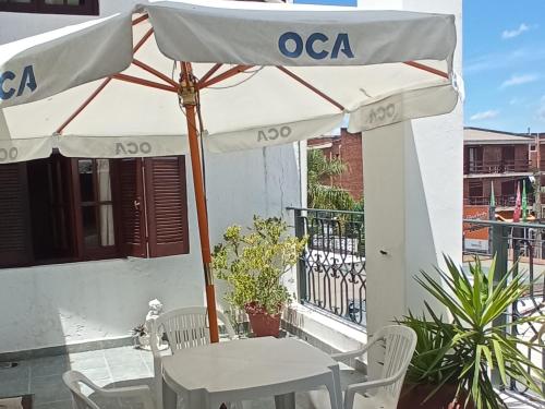 a table with an umbrella in front of a building at Apart Hotel Géminis in Termas del Daymán