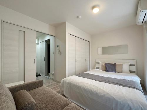 een slaapkamer met een bed en een bank bij bHOTEL Yutori - Good Apartment for 3 people with free wifi in Onomichi