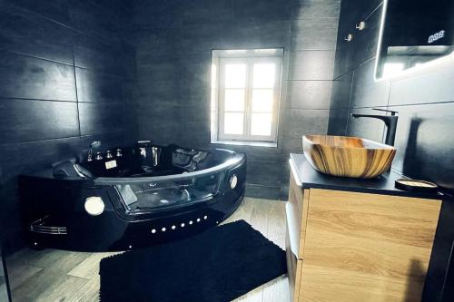 a black bathroom with a wooden sink and a tub at Love Room Le Chalet / Jacuzzi / Sauna in Château-Landon