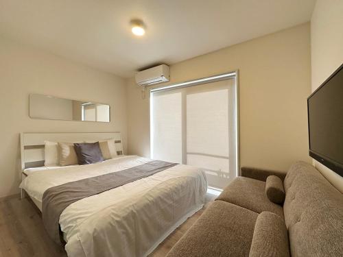 a bedroom with a bed and a window and a couch at Yutori by b hotel - Good Apartment for 3 people with free wifi in Onomichi